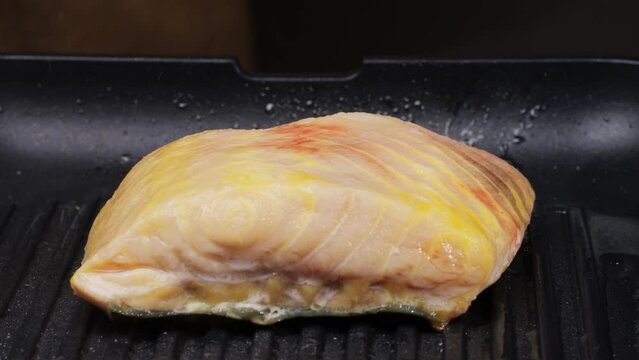 Cooking fillet sturgeon beluga white fat fish on grill or frying pan with oil close-up. Roast healthy food concept. Fry sturgeon, hake, cod fish steak pieces fillet. Healthy diet