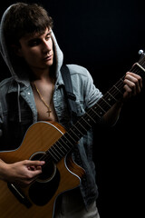 Obraz premium Shirtless young man in denim jacket playing guitar in photo studio