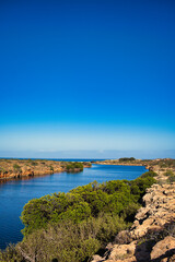 The mouth of Yardie Creek in Cape Range National Park, Western Australia. Rocks with stunted outback vegetation, in the distance the Indian Ocean
