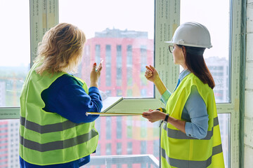 Two female industrial workers taking measurements of windows for decoration