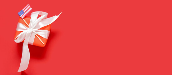 Obraz premium Gift box with beautiful bow and USA flag on red background. American Independence Day