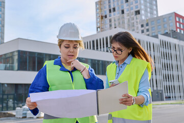 Two confident women talking working on construction of residential office building