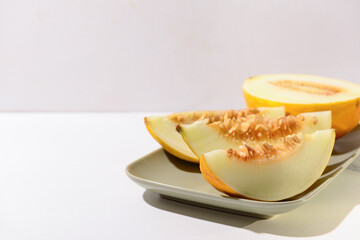 Plate with pieces of sweet melon on white background