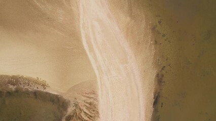 Top down aerial view of a sandy shoreline featuring beautiful textures and natural lines. Serene and tranquil coastal landscape. - Powered by Adobe