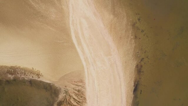 Top down aerial view of a sandy shoreline featuring beautiful textures and natural lines. Serene and tranquil coastal landscape.