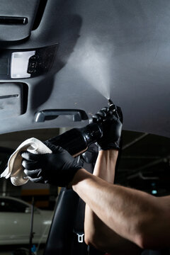 Detailing car headliner covering. Spraying detergent on the headliner in car. Hand cleans car ceiling with detergent and microfiber rug.