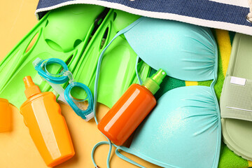 Bottles of sunscreen cream with beach accessories on orange background