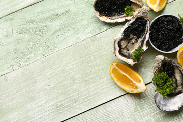 Tasty oysters with lemon and black caviar on green wooden background