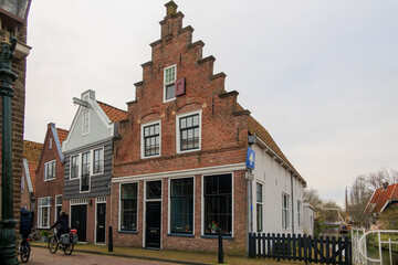 Cyclists ride past a house with a clinker gable in the Dutch town of Edam