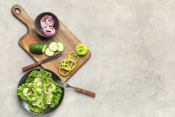 Bowl of tasty vegetable salad and ingredients on grey background