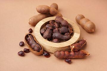 Bowl of tasty tamarinds and seeds on brown background