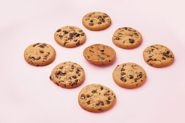 Tasty cookies with chocolate chips on pink background
