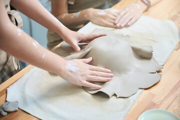Females hands working with clay making ceramic plate