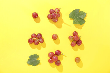Tasty ripe grapes and leaves on yellow background