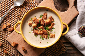 Pot of tasty cream soup with croutons on table