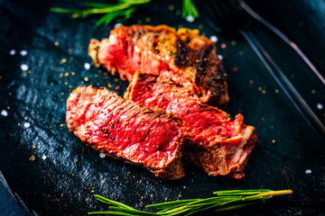 Barbecue grilled and sliced wagyu Rib Eye beef meat steak on a plate. Dark background. Top view.