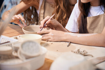 Women sculptors creating ceramic tableware in pottery studio
