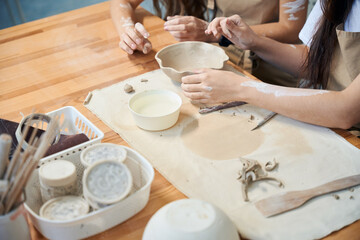 Unrecognizable women artists working with clay shaping handmade dishes