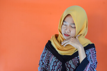 Young Asian woman standing over orange background rubbing eyes because of fatigue and headache, sleepy and tired expression