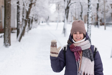 Obraz premium Young smiling beautiful woman wearing scarf outdoors during snowfall