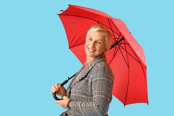 Beautiful mature woman with umbrella on blue background