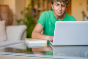 Person in Green Shirt Working on Laptop.Casual work from home scene featuring a laptop and a person in green.