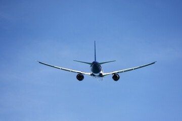 Airplane flying in blue sky, rear view. Passenger plane at flight, travel concept