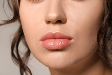 Fototapeta premium Beautiful young woman with nude lipstick on grey background, closeup
