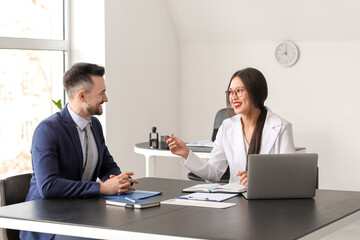 Human resources manager interviewing male applicant at table in office