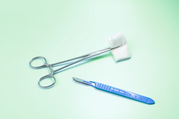 A pair of scissors and a pair of surgical scissors are on a green surface