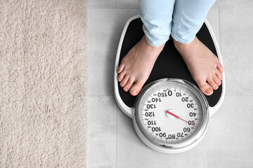Young woman standing on scales at home, top view. Weight loss concept