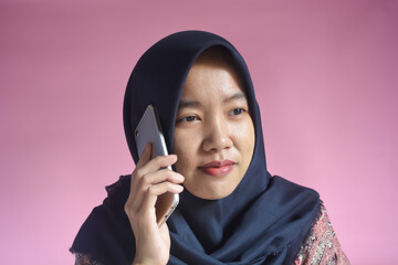 Portrait of an Asian woman with a happy gesture playing with a smartphone in her hand