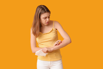 Young woman with skin allergy and tissue on yellow background