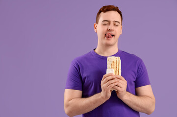 Young thoughtful man holding doner kebab on purple background