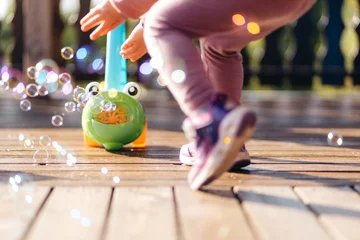 Fototapeten Sommer The legs of a child in front of a soap bubble toy blowing bubbles  © Benjamin