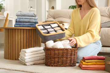 Woman with different clean clothes sitting on floor at home