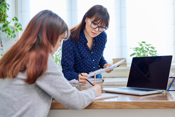 Female teacher mentor teaching young teenage girl student using laptop computer