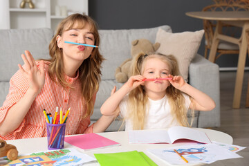 Nanny and little girl with pencils having fun at home