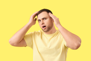 Fototapeta premium Worried young man with hair loss problem on yellow background