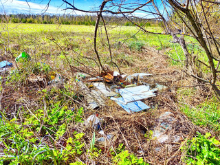 Garbage and debris litter the ground of a grassy meadow, highlighting the problem of pollution in natural environments