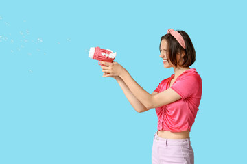 Teenage girl with soap bubble gun on blue background