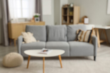 Blurred view of living room with grey sofa and table