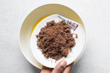 Overhead view of Dark brown sugar in a white plate on a white marble table, top view of sugar for baking in a white plate