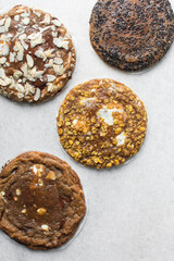 Overhead view of different types of sugar cookies, almond chocolate chip cookies, cornflake white chocolate chip cookie, black sesame sugar cookie on parchment paper