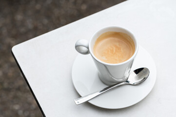 Cup of coffee and a spoonon a hardboard white table, Belgium