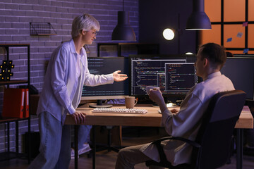 Young programmers working in office at night