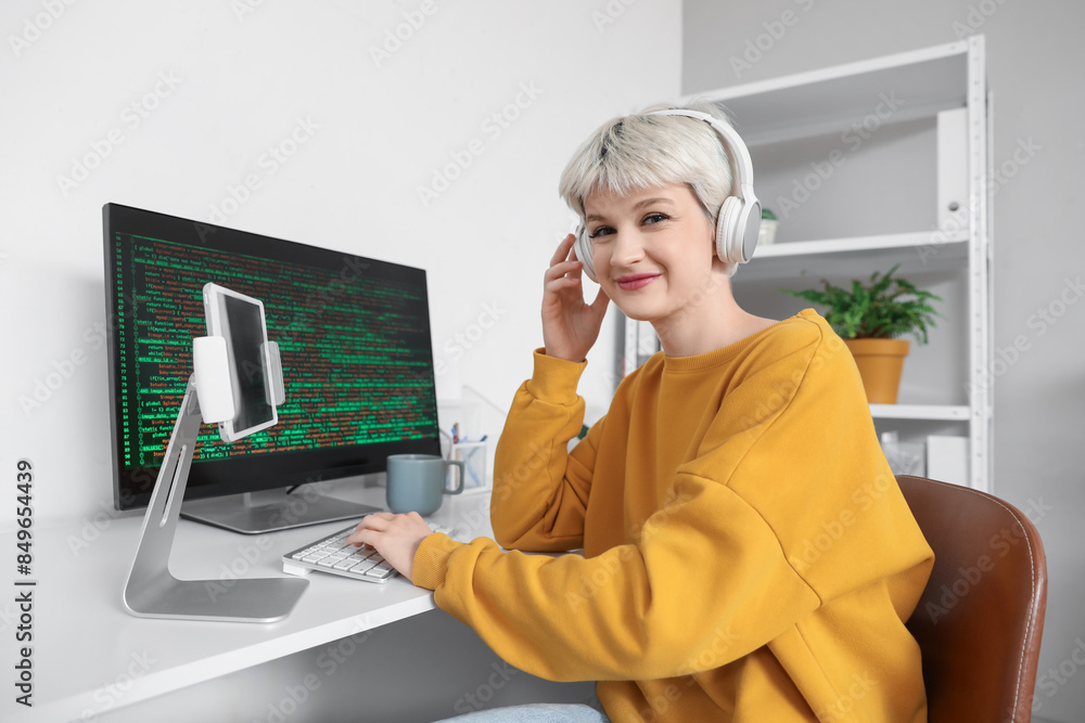 Poster female programmer with headphones and computer working in office