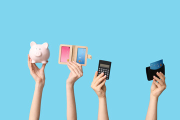 Female hands with credit cards, calculator and piggy bank on blue background