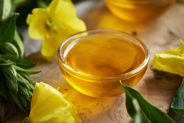 Evening primrose oil in a glass bowl with fresh Oenothera biennis flowers