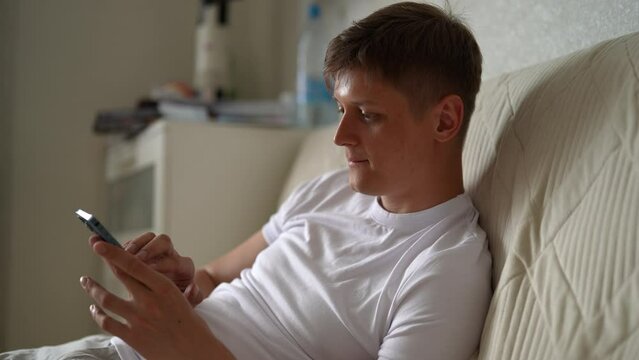 Focused crypto trader male clicking on mobile phone screen to farming new Hamster Kombat cryptocurrency coin in online application. Serious young man extract crypto coins using smartphone.
